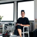 Confident young professional woman enjoying a coffee break in a modern office environment.